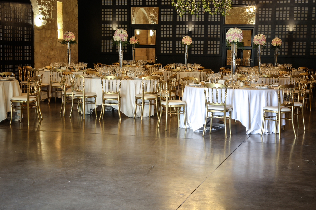 Salle de mariage décorée de centre de table romantique chic avec des boules de fleurs sur des vases hauts.