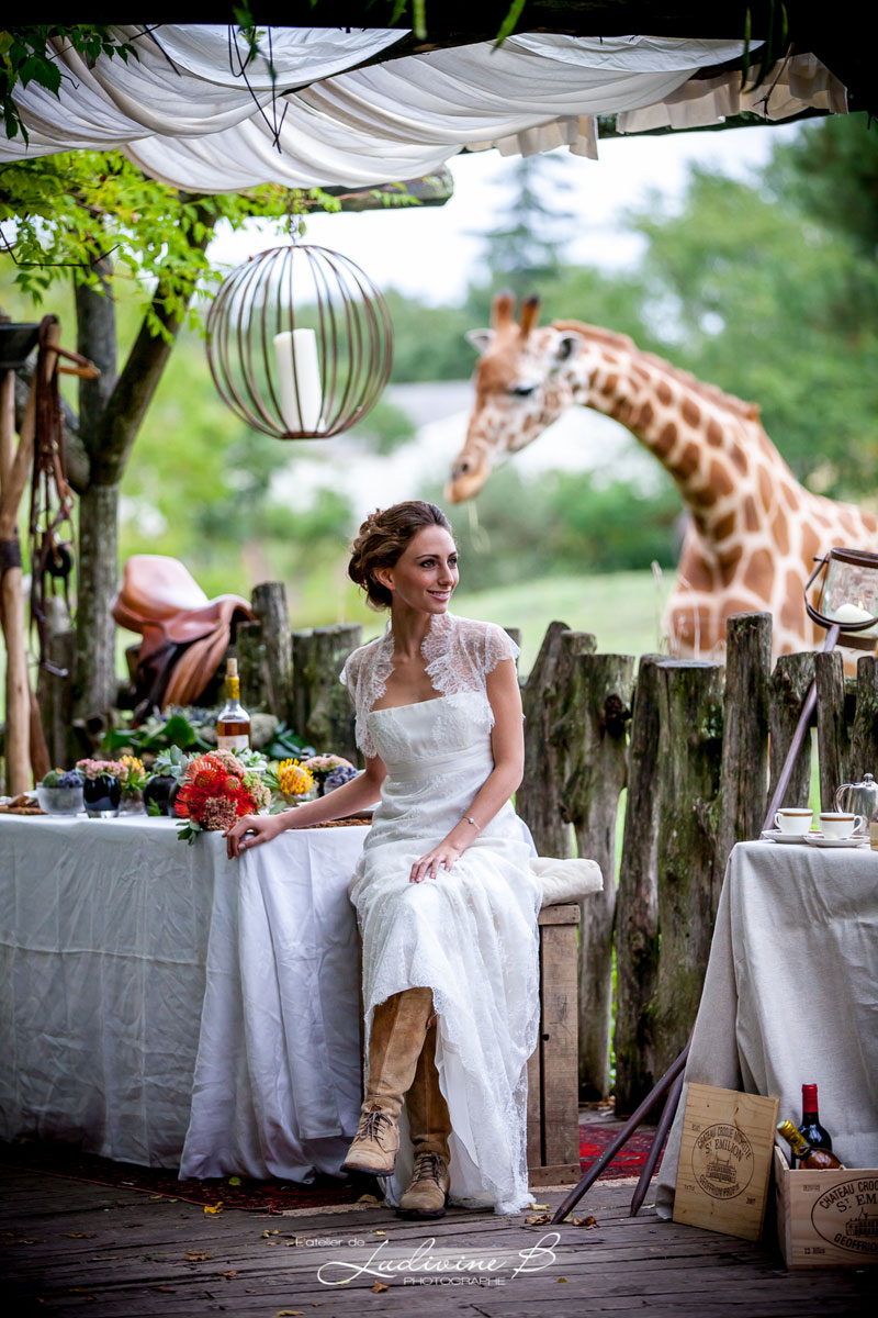Décoration de mariage au thème safari chic avec une mariée, une girafe dans un extérieur bohème et sauvage.