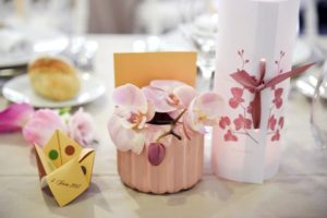 Composition Florale Sur Le Thème Du Japon Lors D'une Réception Avec L'orchidée Rose Et Une Origami Comme Menu De Mariage.
