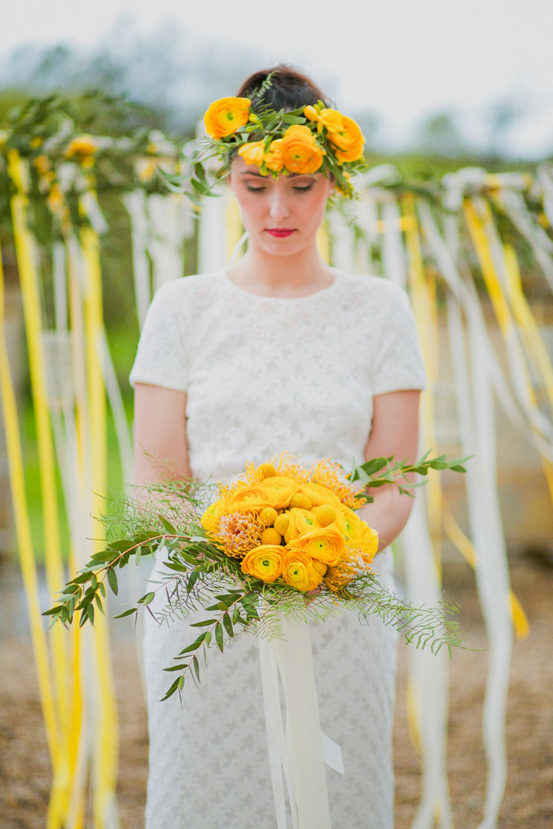 Bouquet de mariée jaune et bohème avec la craspedia et la renoncule lors de mariage de printemps.