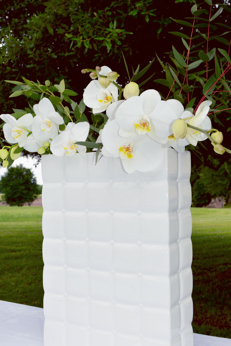 Bouquet d'orchidées blanches en déco de réception de mariage en plein air.