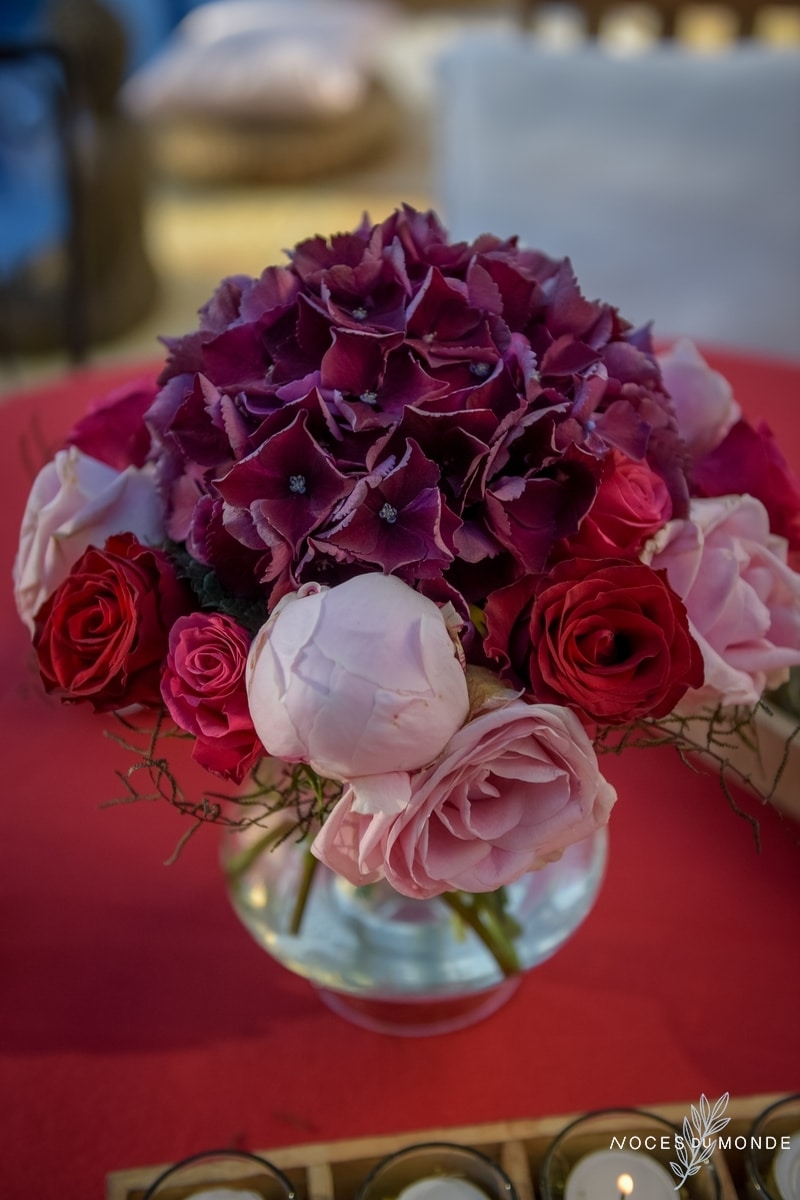 Centre de table de mariage au thème vigne et vin en hortensia violet et rose rouge.