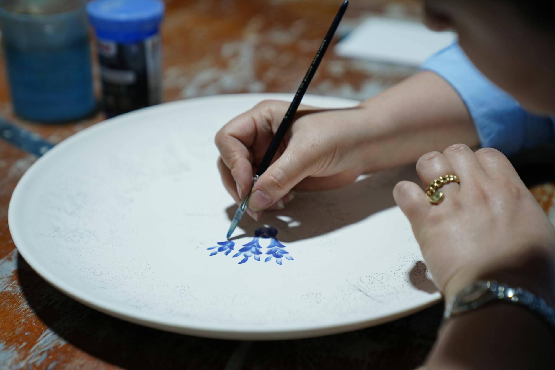Mains d'artisan peignant une assiette céramique traditionnelle italienne à Deruta