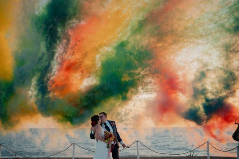 Couple de mariés entouré de fumigènes colorés lors d'une cérémonie en plein air